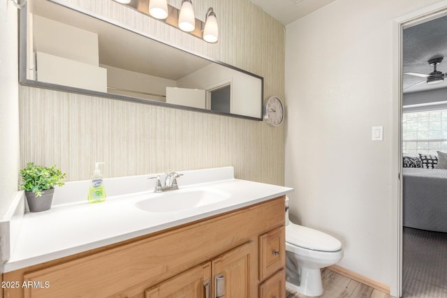 bathroom featuring ceiling fan, vanity, toilet, and wood-type flooring