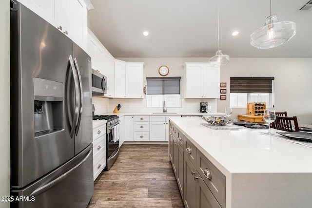 1005 E Weldon Ave, Phoenix, AZ 85014 - kitchen with appliances with stainless steel finishes, a sink, light countertops, dark wood-type flooring, and white cabinets