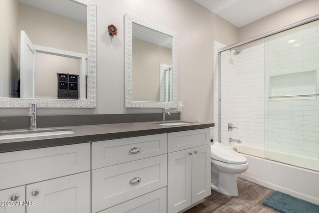 1005 E Weldon Ave, Phoenix, AZ 85014 - full bathroom with double vanity, toilet, wood finished floors, and combined bath / shower with glass door