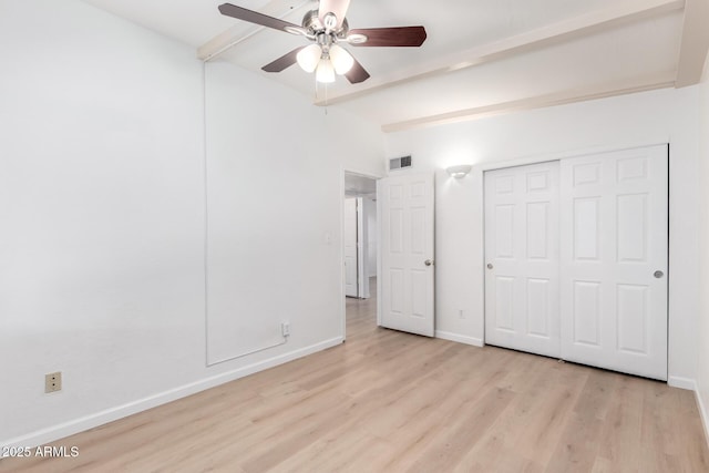 unfurnished bedroom with ceiling fan, lofted ceiling with beams, a closet, and light wood-type flooring