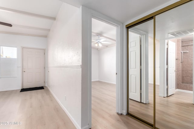 corridor with beam ceiling and light wood-type flooring