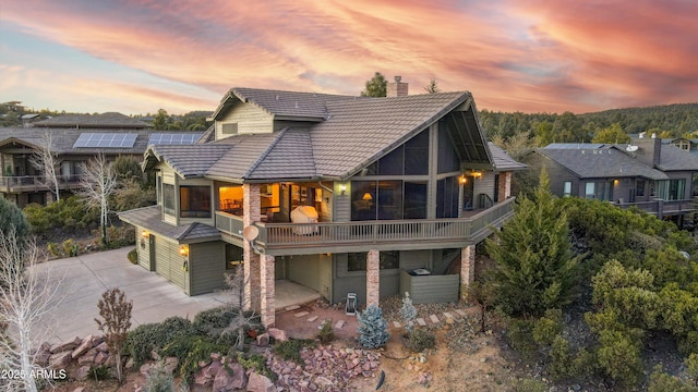 back house at dusk with a balcony and a patio area