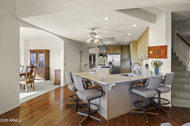 kitchen with stainless steel fridge, ceiling fan, sink, hardwood / wood-style flooring, and a breakfast bar area