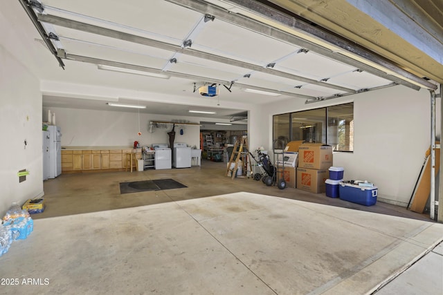 garage with white fridge, independent washer and dryer, and a garage door opener