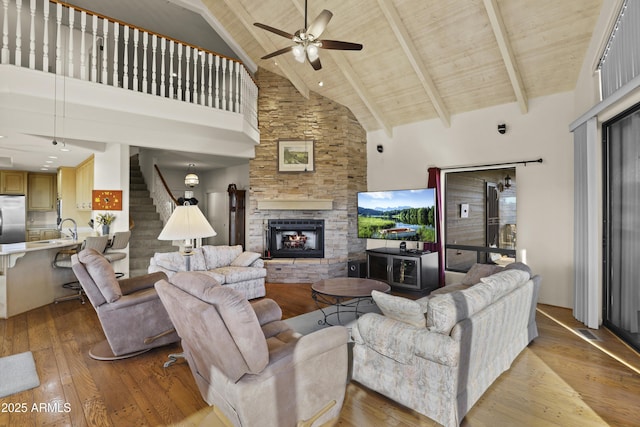 living room with ceiling fan, wooden ceiling, light hardwood / wood-style flooring, beamed ceiling, and high vaulted ceiling