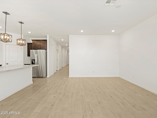 unfurnished living room with a notable chandelier and light wood-type flooring