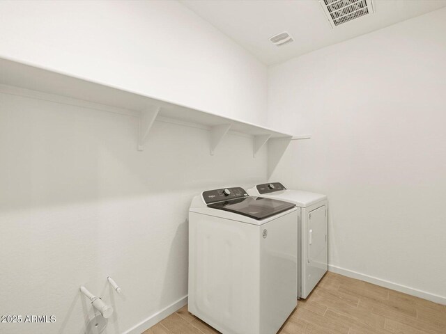 laundry area featuring washing machine and clothes dryer and light wood-type flooring