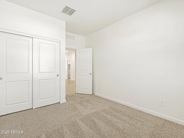 unfurnished bedroom featuring light colored carpet and a closet