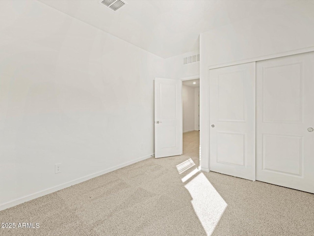 unfurnished bedroom with light colored carpet and a closet