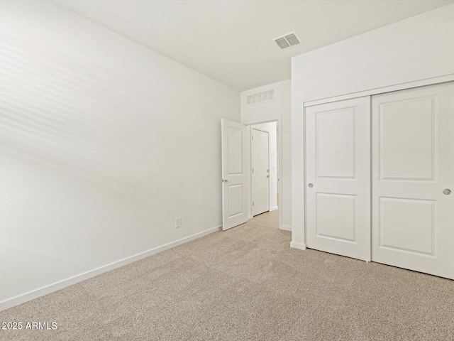 unfurnished bedroom featuring light carpet and a closet