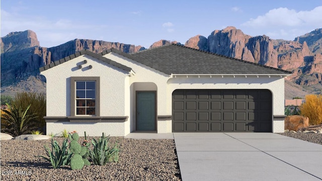 view of front facade featuring concrete driveway, an attached garage, a mountain view, and stucco siding