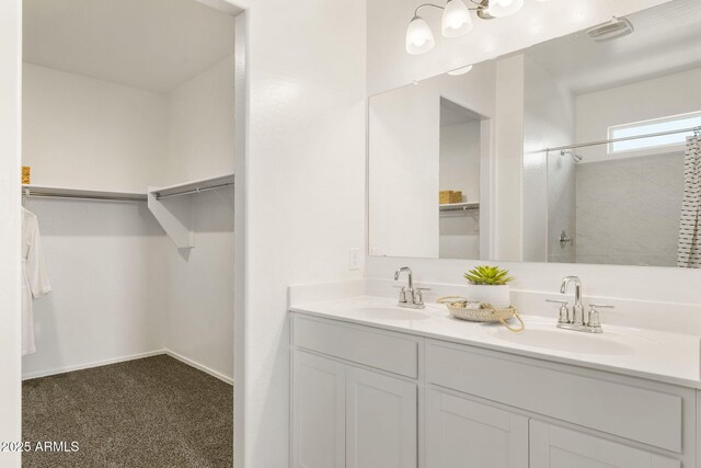 bathroom featuring double vanity, a sink, and a walk in closet