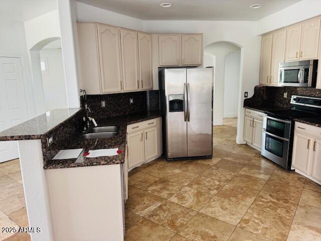 3502 W Belle Ave, San Tan Valley, AZ 85144 - kitchen with appliances with stainless steel finishes, arched walkways, a sink, a peninsula, and tasteful backsplash