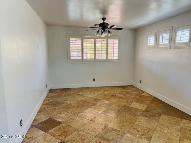 3502 W Belle Ave, San Tan Valley, AZ 85144 - spare room featuring healthy amount of natural light, a ceiling fan, baseboards, and light stone finish flooring