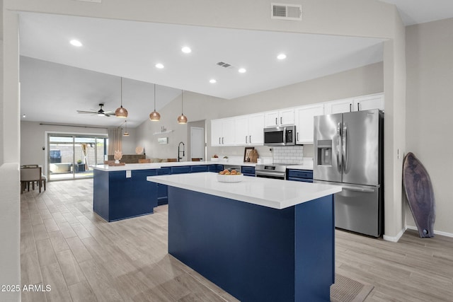 kitchen with appliances with stainless steel finishes, a center island, white cabinets, decorative light fixtures, and kitchen peninsula