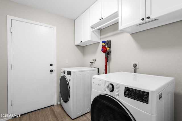 laundry room featuring cabinets, washer and dryer, and light hardwood / wood-style floors