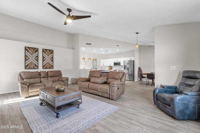 living room with light hardwood / wood-style flooring, vaulted ceiling, and ceiling fan