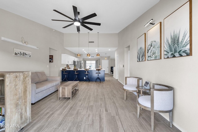 living room with high vaulted ceiling, ceiling fan, and light hardwood / wood-style flooring