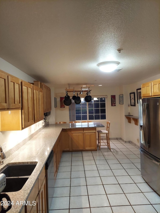 kitchen featuring kitchen peninsula, sink, stainless steel fridge, a textured ceiling, and light tile patterned floors