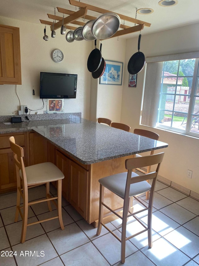 kitchen featuring a breakfast bar, dark stone counters, and light tile patterned floors