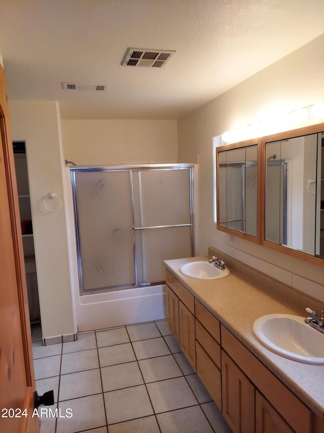 bathroom with tile patterned flooring, double sink vanity, and enclosed tub / shower combo