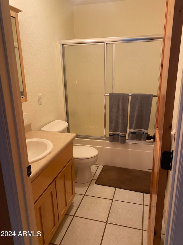 full bathroom featuring vanity, combined bath / shower with glass door, tile patterned flooring, and toilet