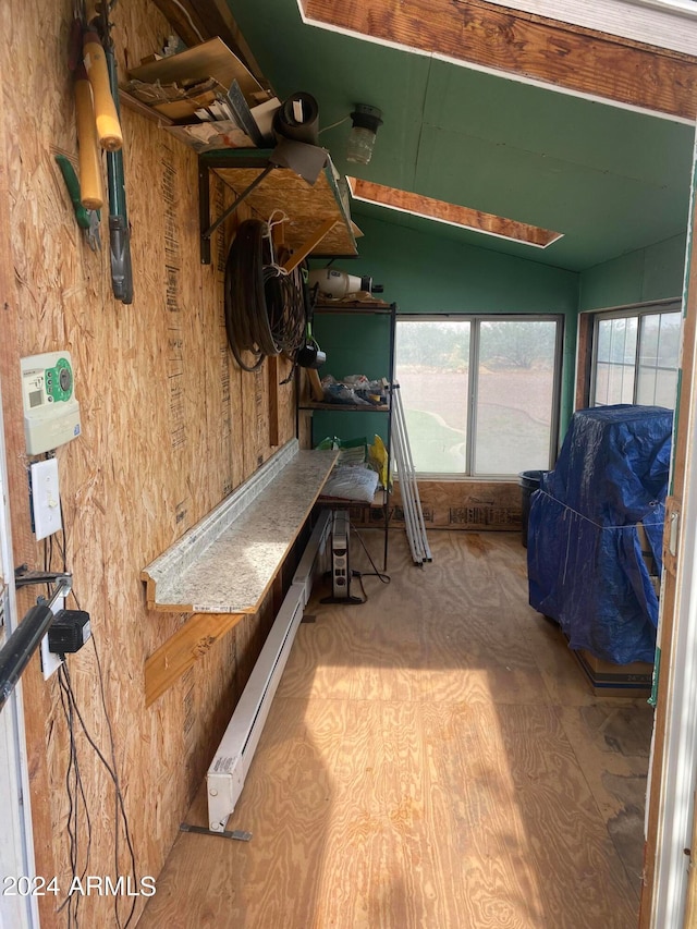 interior space with a baseboard heating unit, lofted ceiling, and hardwood / wood-style floors