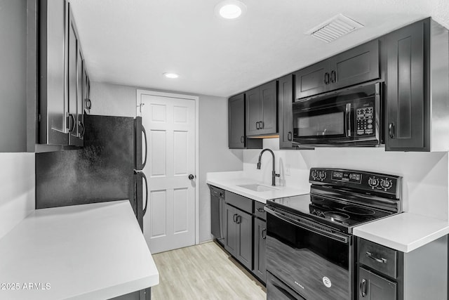 kitchen featuring sink, light wood-type flooring, and black appliances