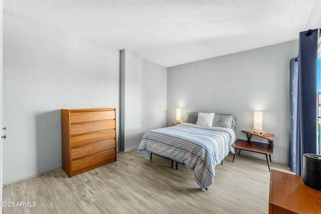 bedroom with a textured ceiling and light hardwood / wood-style flooring