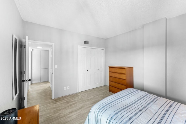 bedroom featuring light hardwood / wood-style floors, a closet, and a textured ceiling