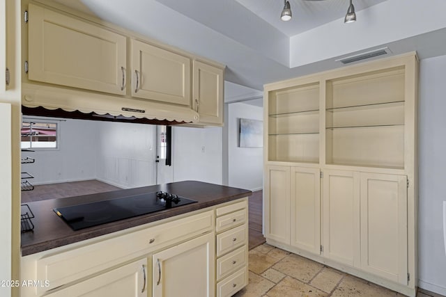 1215 E Geneva Dr, Tempe, AZ 85282 - kitchen featuring black electric cooktop, dark countertops, under cabinet range hood, stone tile floors, and cream cabinets