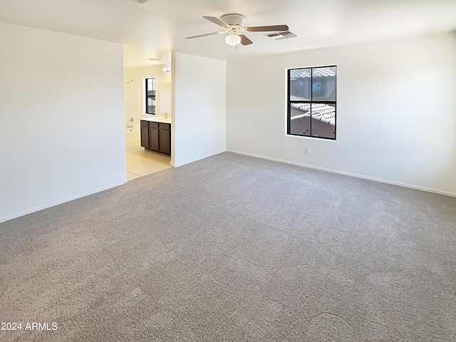 empty room featuring ceiling fan and light colored carpet