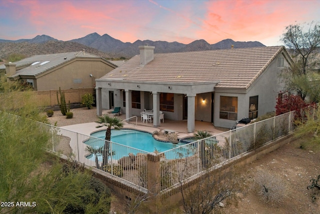 back of property with a patio area, a fenced in pool, a mountain view, and a fenced backyard