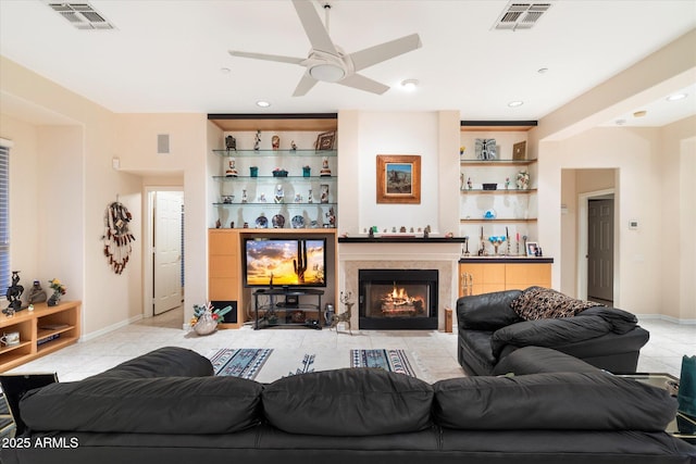 living room featuring built in features, visible vents, light tile patterned floors, and a tile fireplace