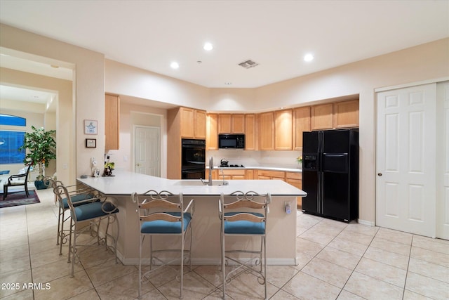 kitchen with black appliances, a breakfast bar area, a peninsula, and light brown cabinetry