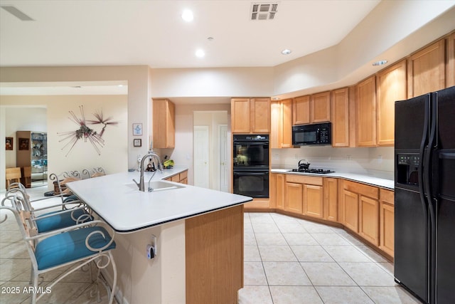 kitchen with light tile patterned floors, visible vents, a peninsula, a sink, and black appliances