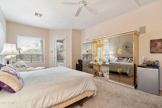 carpeted bedroom with a closet, visible vents, freestanding refrigerator, and a ceiling fan