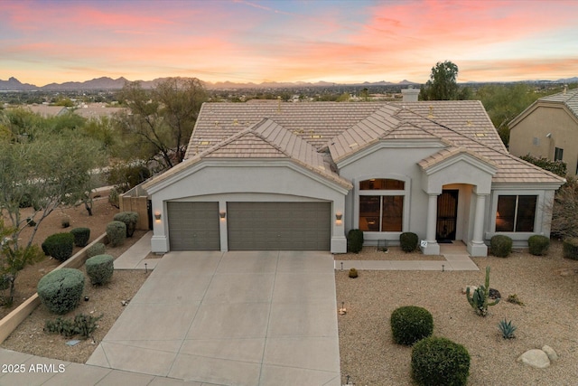 mediterranean / spanish house with driveway, stucco siding, a garage, a tile roof, and a mountain view