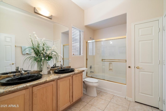 bathroom with a sink, toilet, double vanity, and tile patterned flooring