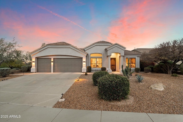 mediterranean / spanish-style house with a tiled roof, a garage, concrete driveway, and stucco siding