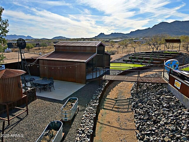 view of yard featuring an outbuilding, a mountain view, a patio, and fence