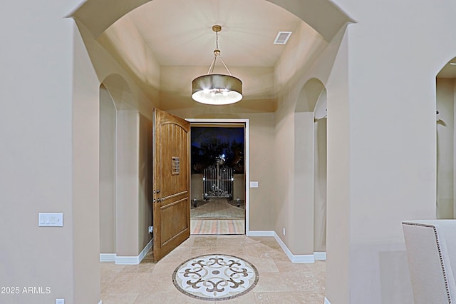 corridor with arched walkways, visible vents, and baseboards