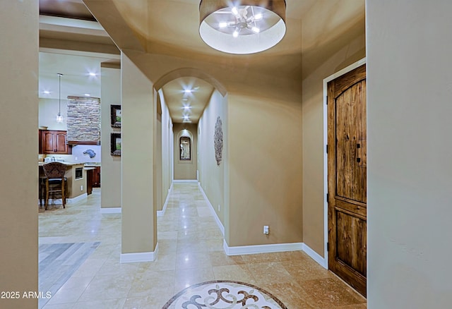 foyer featuring baseboards and arched walkways