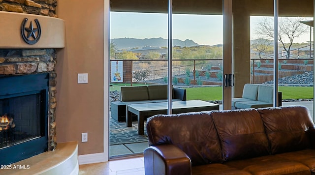 living area featuring a mountain view, baseboards, a healthy amount of sunlight, and a fireplace