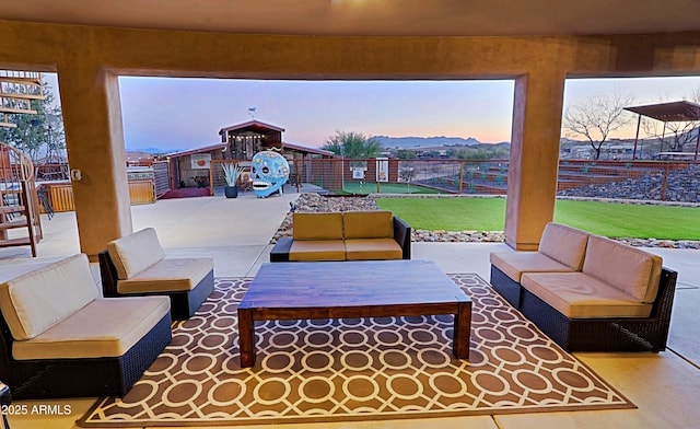 patio terrace at dusk with a yard, an outdoor hangout area, and fence