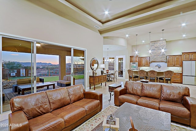 living area featuring arched walkways, visible vents, a notable chandelier, and a towering ceiling