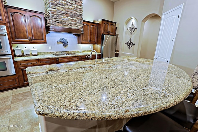 kitchen with a breakfast bar area, light stone countertops, appliances with stainless steel finishes, and a spacious island