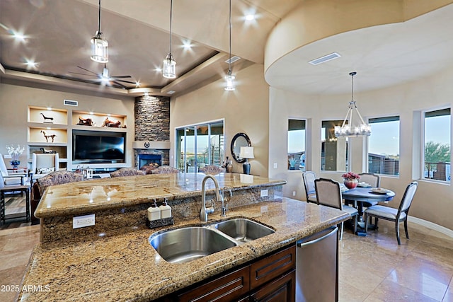 kitchen featuring visible vents, a sink, dark brown cabinetry, pendant lighting, and a raised ceiling