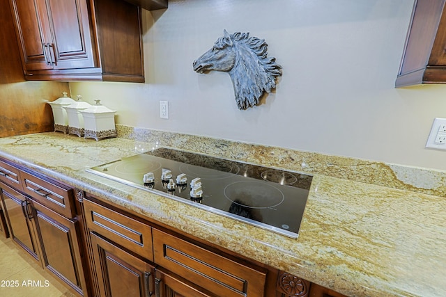 kitchen with black electric stovetop, light stone counters, and light tile patterned floors