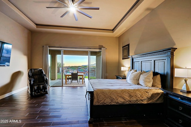 unfurnished bedroom featuring dark wood finished floors, access to exterior, baseboards, and a tray ceiling